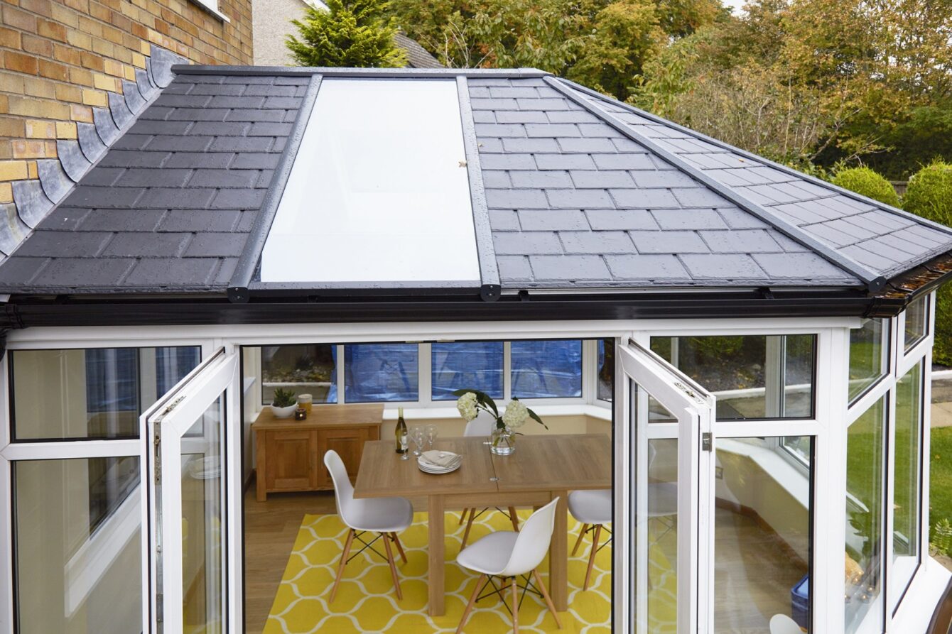 Close up of a conservatory roof featuring a single glazed panel on each side, inside is a modern dining space.]