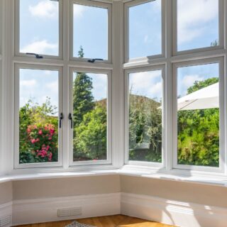 A bay window seen from the inside looking over a pretty garden, the windows are constructed in high quality PVCu, with robust handles.
