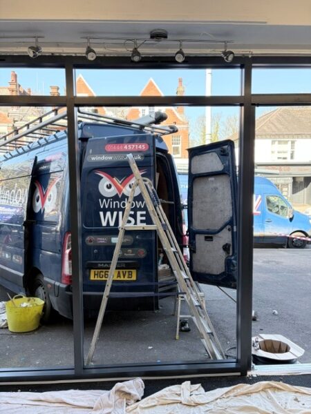 A Window Wise van with ladders on top and rear doors open, outside the shopfront, ready to start work.